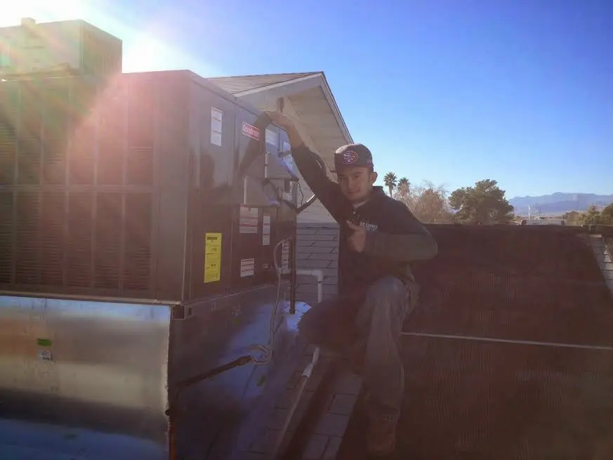 HVAC technician performing AC Tune-Up on a rooftop unit in Kendall West