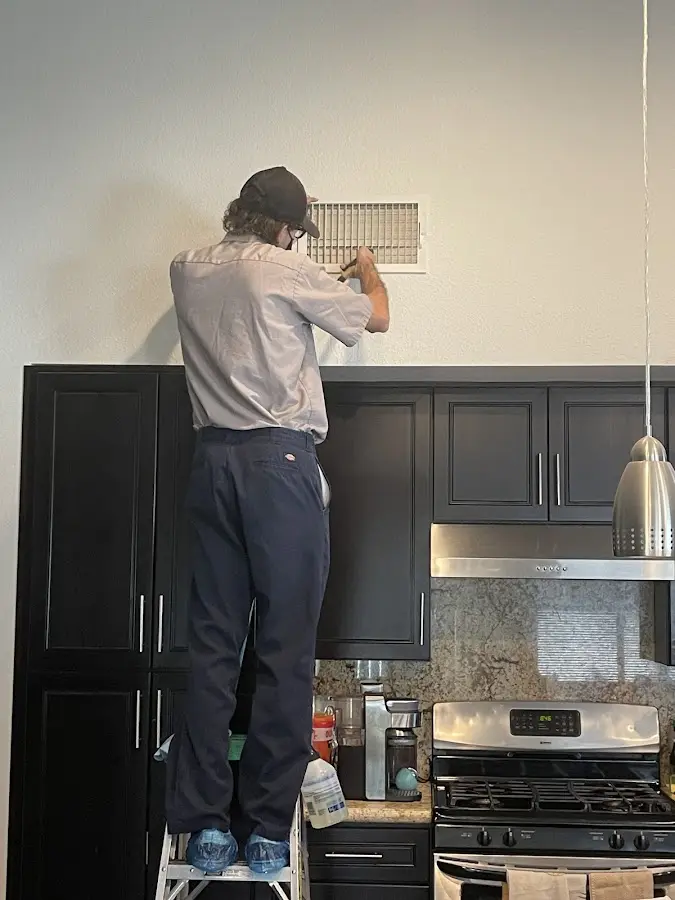 Technician inspecting an air vent during HVAC service in Kendall West